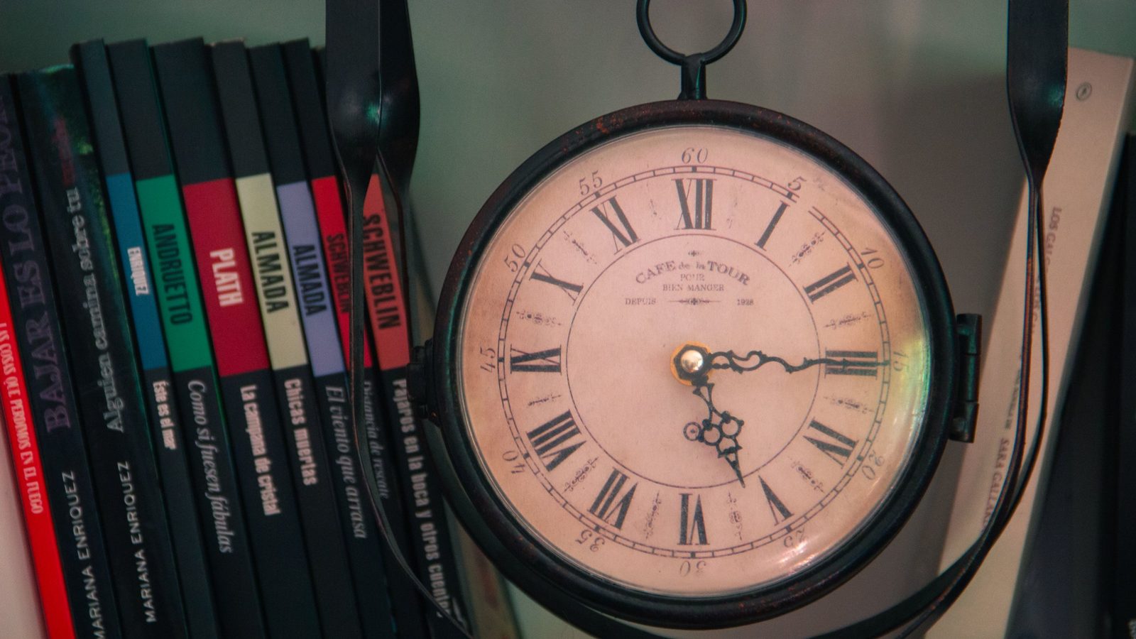 Reloj antiguo junto a una hilera de libros